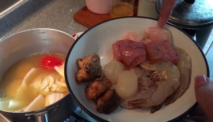 Add the deep-fried grouper meat, fish liver, fish roe, scallops, and prawns to the boiling soup. Cook until seafood is done.