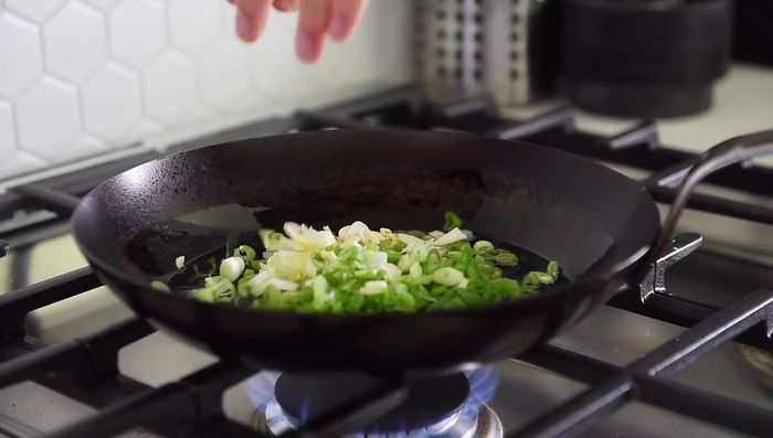 Sauté green onion, garlic, ginger, and dried chili peppers for about 30 seconds.