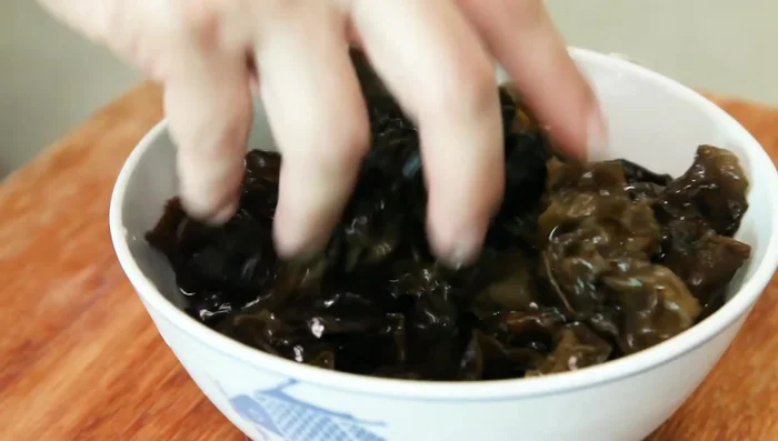 After 30 minutes, the black fungus will have tripled in size. Pick out and tear up the bigger pieces, discarding any hard bits. Rinse well.