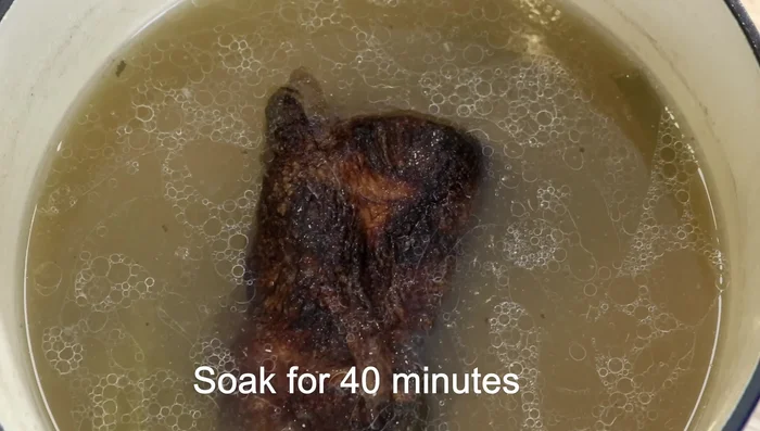Place the pork in the warm broth from earlier, skin-side down, and let it soak for 40 minutes.
