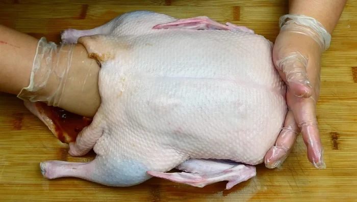 Give the duck a final rub, ensuring ingredients reach the top. Stitch up the duck using a metal skewer.