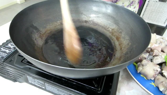 Fry pig's feet: Add the pre-boiled pig's feet to the wok and stir-fry lightly with the caramelized sugar.
