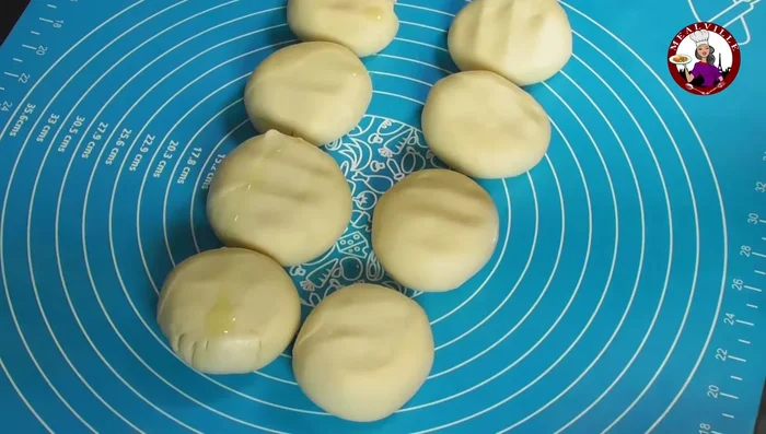 Slightly flatten each ball, coat with oil, cover with a damp cloth, and let rest for 10 minutes.