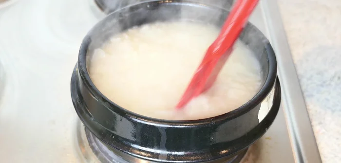 Stir the rice porridge continuously in a clockwise direction. Cover the pot and cook on low heat for about an hour until the rice is completely dissolved and gooey.