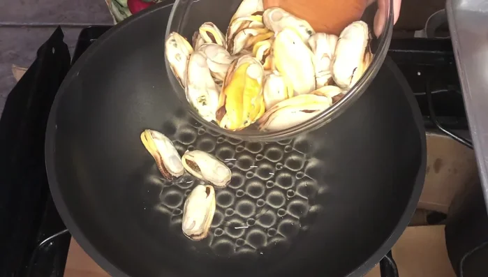 Add oil to a hot wok and add the mussels. Cook for a minute to remove the fishy smell, then remove the mussels.