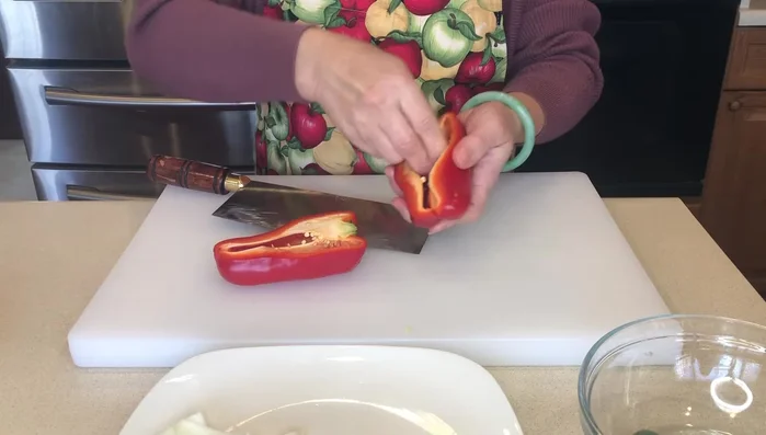 Cut the bell pepper in half, remove the core, and slice it similarly to the onions.