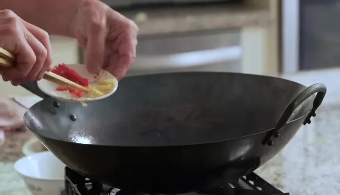 Pour out the blanching water from the wok. Add garlic, ginger, and chili pepper to the wok and stir-fry until aromatic (636.44).