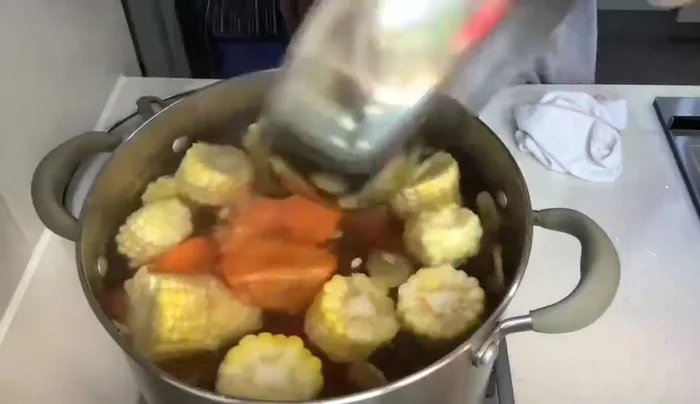 Combine the blanched pork bones, sweet corn, and carrots in a pot. Bring to a boil.
