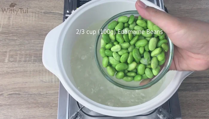 Add 100 grams of frozen edamame beans to the spiced water and simmer on low heat for 5 minutes.