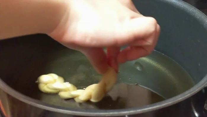 Fry the dough twists over low-medium heat for about 18 minutes, flipping occasionally, until golden brown. Avoid high heat to prevent burning the outside before the inside is cooked.