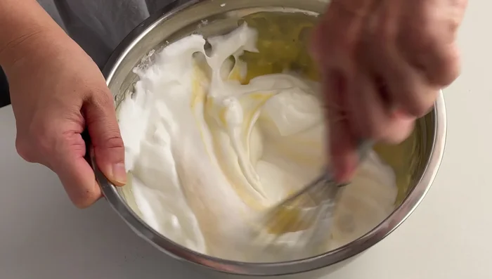 Gently fold 1/3 of the beaten egg whites into the egg yolk batter until well combined. Then, pour the batter into the remaining egg whites and fold gently until well combined.