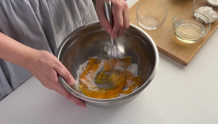 Add 50g castor sugar to egg yolks, mix well. Add 80g sunflower oil, mix well. Add 160g plain flour, 20g corn starch, 1/2 tsp baking powder (if using), 1 tsp vanilla essence, and 120ml water. Mix until no dry flour clumps remain. Set aside.