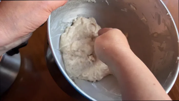 Take a tablespoon of fish batter, create a divot, add a meatball, and carefully wrap the batter around it to form a sphere using your hands. Dip a tablespoon in cold water to help shape the fish balls.
