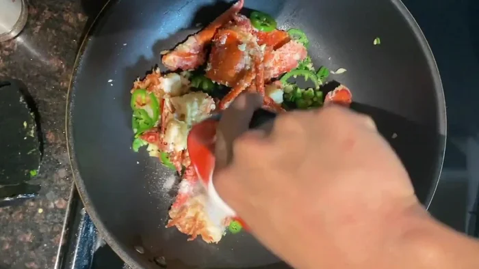 Add the fried lobster to the aromatics, toss with salt and pepper seasoning and sugar.