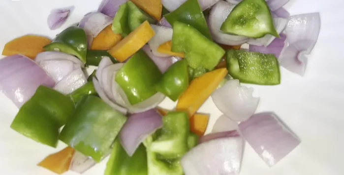 Prepare vegetables: Cut all vegetables (capsicum, carrots, cabbage, green onions, green chilies) into small pieces for both dishes.