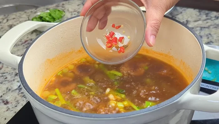 Add Thai chili (if desired) and gai lan leaves. Tear gai lan leaves by hand (if using regular, not baby gai lan).