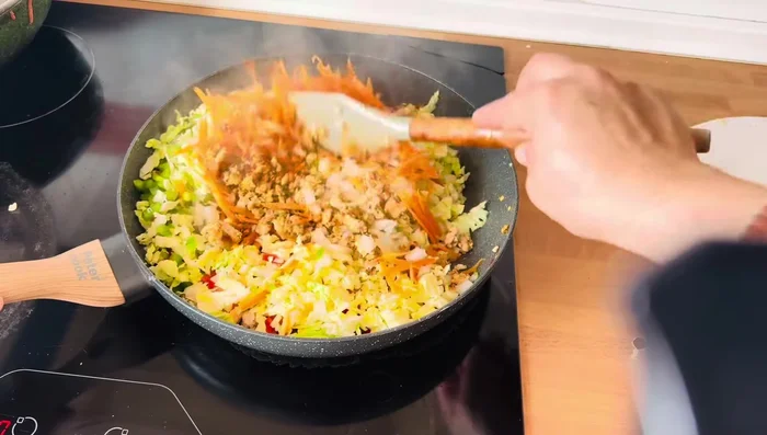 Add the grated carrot, chopped cabbage, onion, and capsicum. Mix well but don't overcook the vegetables.