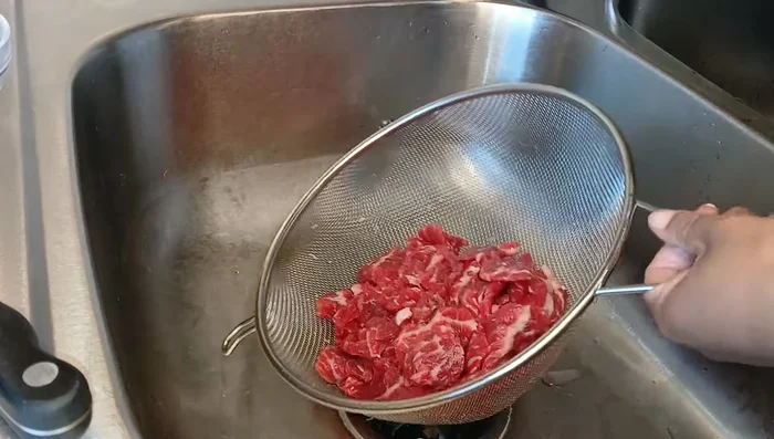 After 30 minutes, rinse the beef in a strainer under cold water to remove excess baking soda and moisture.