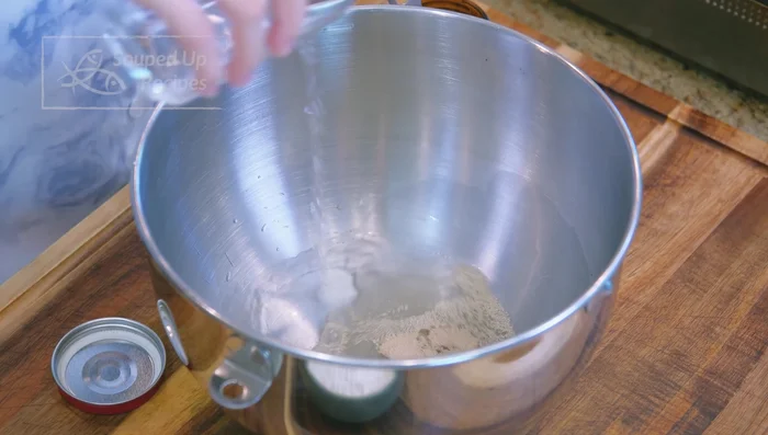 Prepare the buns: Mix yeast and lukewarm water. Let it rest for 5 minutes (active dry yeast). Add soda ash (from heated baking soda) and flour. Mix with a stand mixer (low speed, 8 minutes) or by hand.