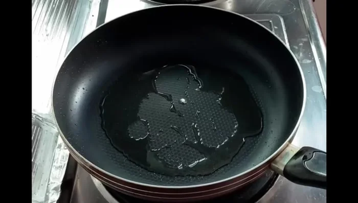 Pour a large spoonful of batter into the hot pan and spread it into a round shape.