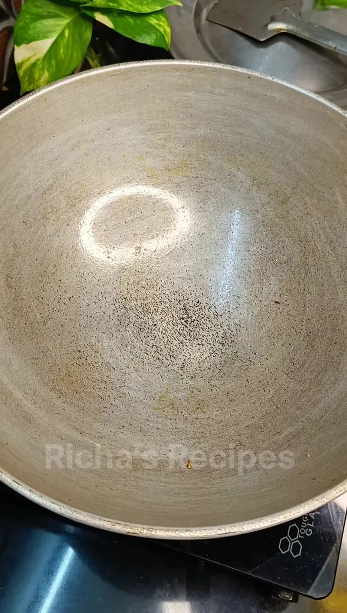 Heat a pan (preferably iron) well. Add 1 tbsp oil, then add finely chopped ginger, garlic, green chili, and red chili. Stir-fry for a short time.