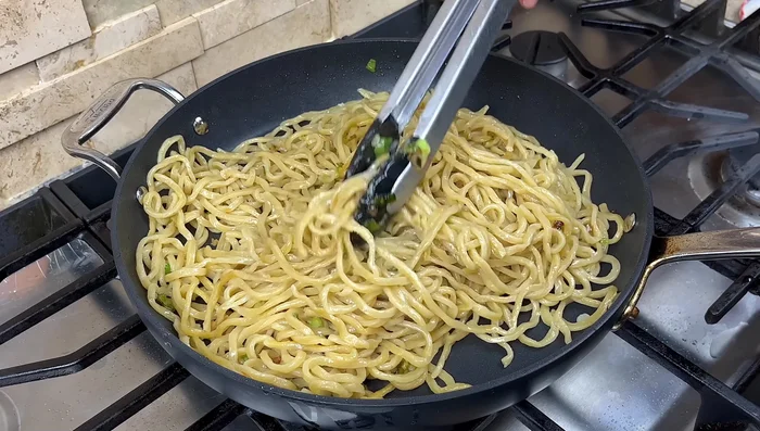 Add sauces and sugar: Add soy sauce, dark soy sauce, and sugar around the pan's edge. Stir-fry until noodles are evenly colored.