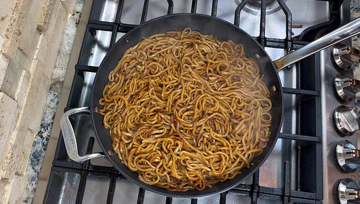 Combine all ingredients: Add the stir-fried onions, bean sprouts, leafy green onions, sesame oil, and black pepper to the pan. Toss to combine.
