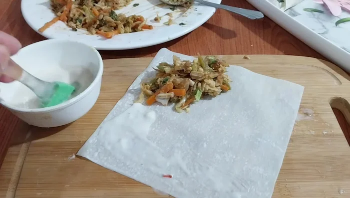 Prepare the roll wrappers by brushing them with a mixture of all-purpose flour and water to prevent them from breaking during the cooking process. Lightly heat the wrapper before filling.