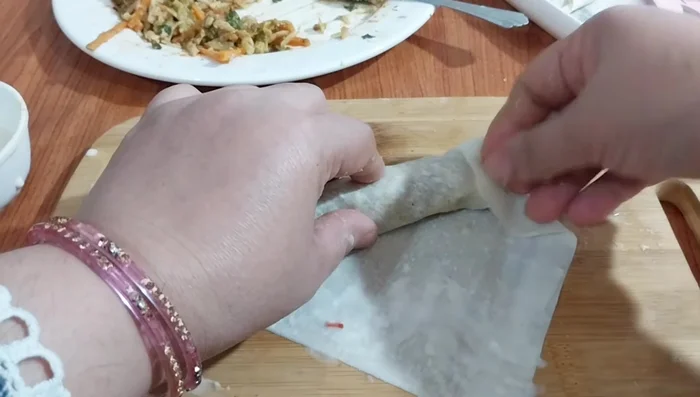 Spread the filling onto the wrapper and roll it tightly, sealing the edges.