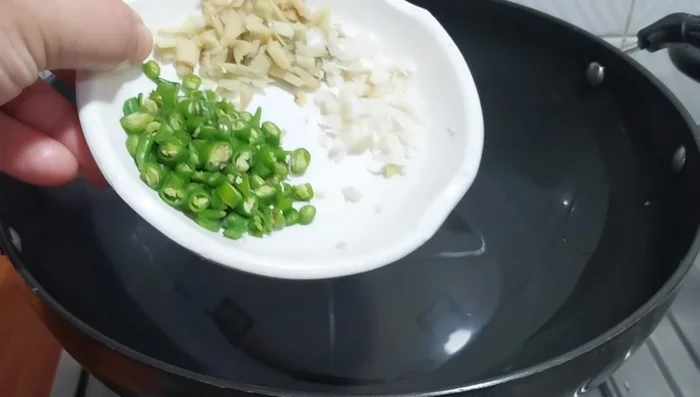 Heat 1 tablespoon of oil in a pan. Add minced garlic, ginger, and green chilies. Fry for 1 minute without browning.