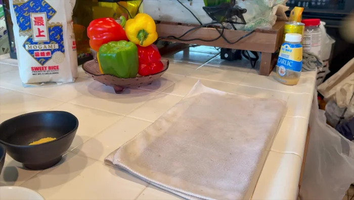 Cut Chinese sausage into bite-sized pieces. Use a towel to prevent the cutting board from slipping.