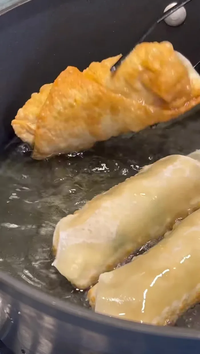 Gently add egg rolls to the hot oil and fry until golden brown and crispy.