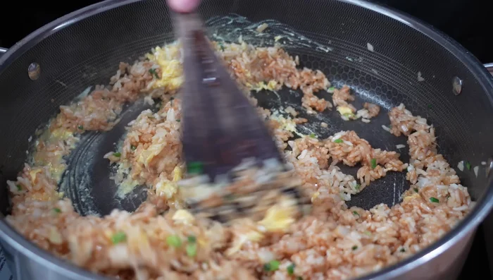 Add scrambled eggs, cooked shrimp, and chopped vegetables to the rice and mix thoroughly.