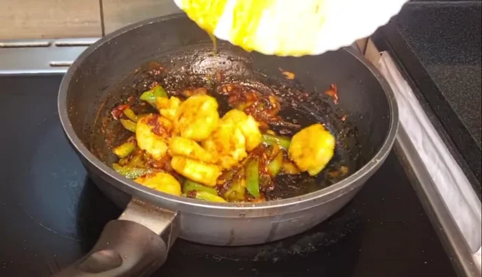 Add the fried prawns to the pan and stir for 1 minute to coat with spices.