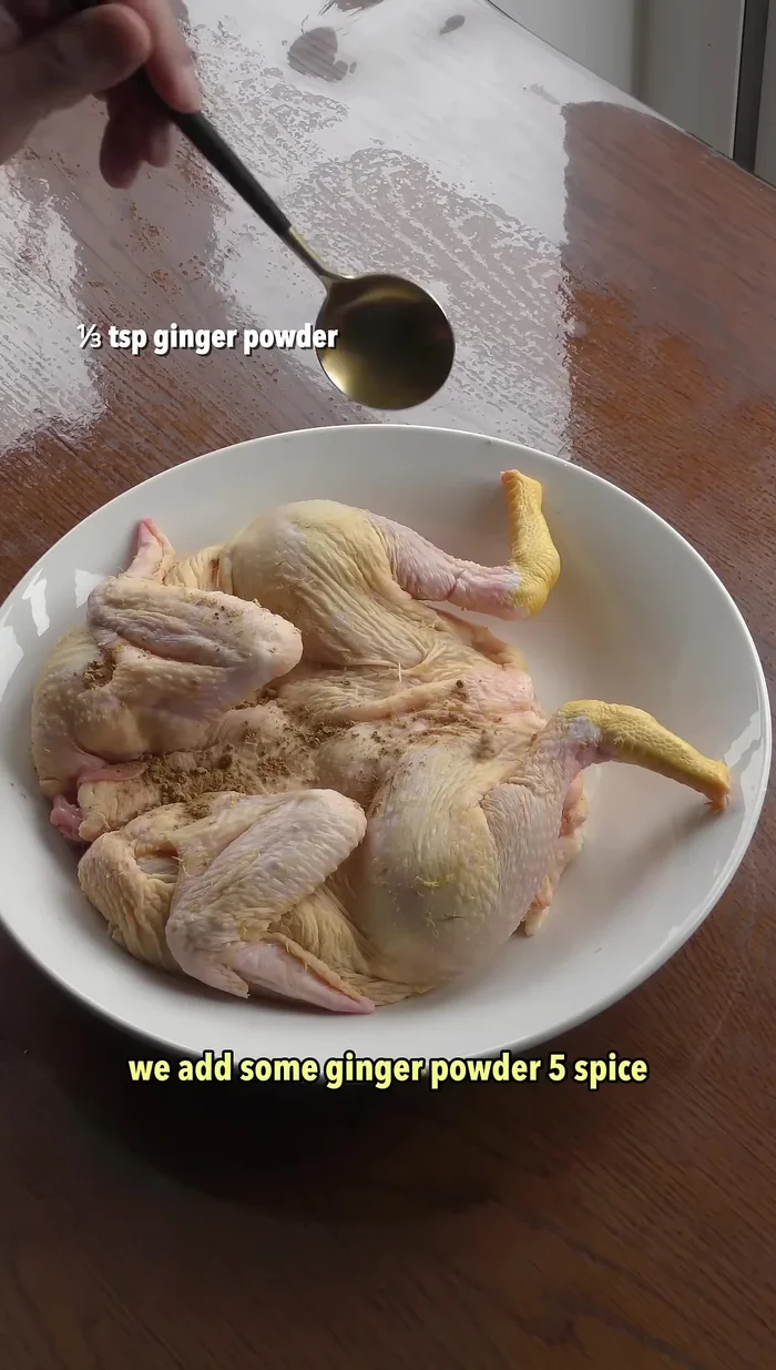 Add ginger powder, five-spice powder, oyster sauce, spring onions, and ginger to the opened chicken.