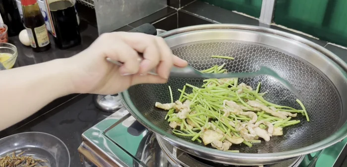 Add spinach stems to the wok and stir-fry for a couple of minutes to soften.
