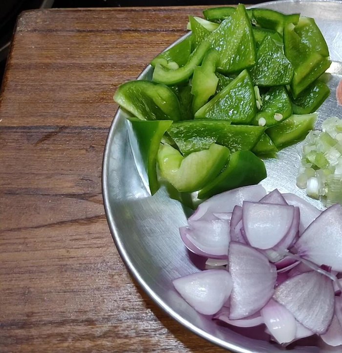 Finely chop green chilies, thinly slice carrots, and cut capsicum and onion into triangles. Chop spring onions finely.
