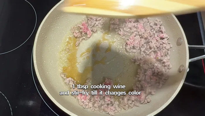 Add the green onions, ginger, and garlic to the pork and stir-fry.