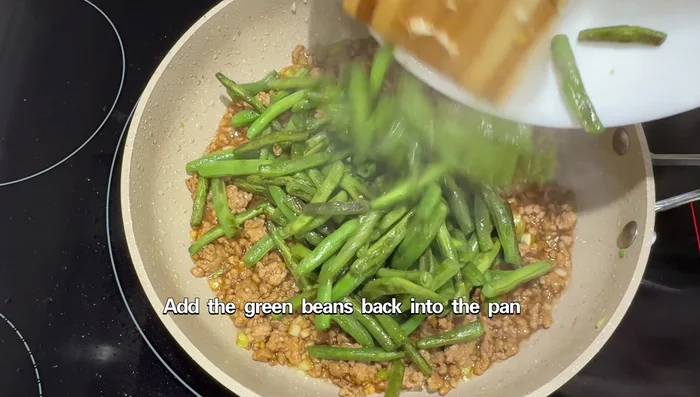 Add the cooked green beans back to the pan and stir-fry everything together.
