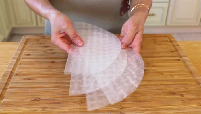 Fold two corners of each rice paper to the center, forming an envelope. Add about 1 tablespoon of shrimp to the center.