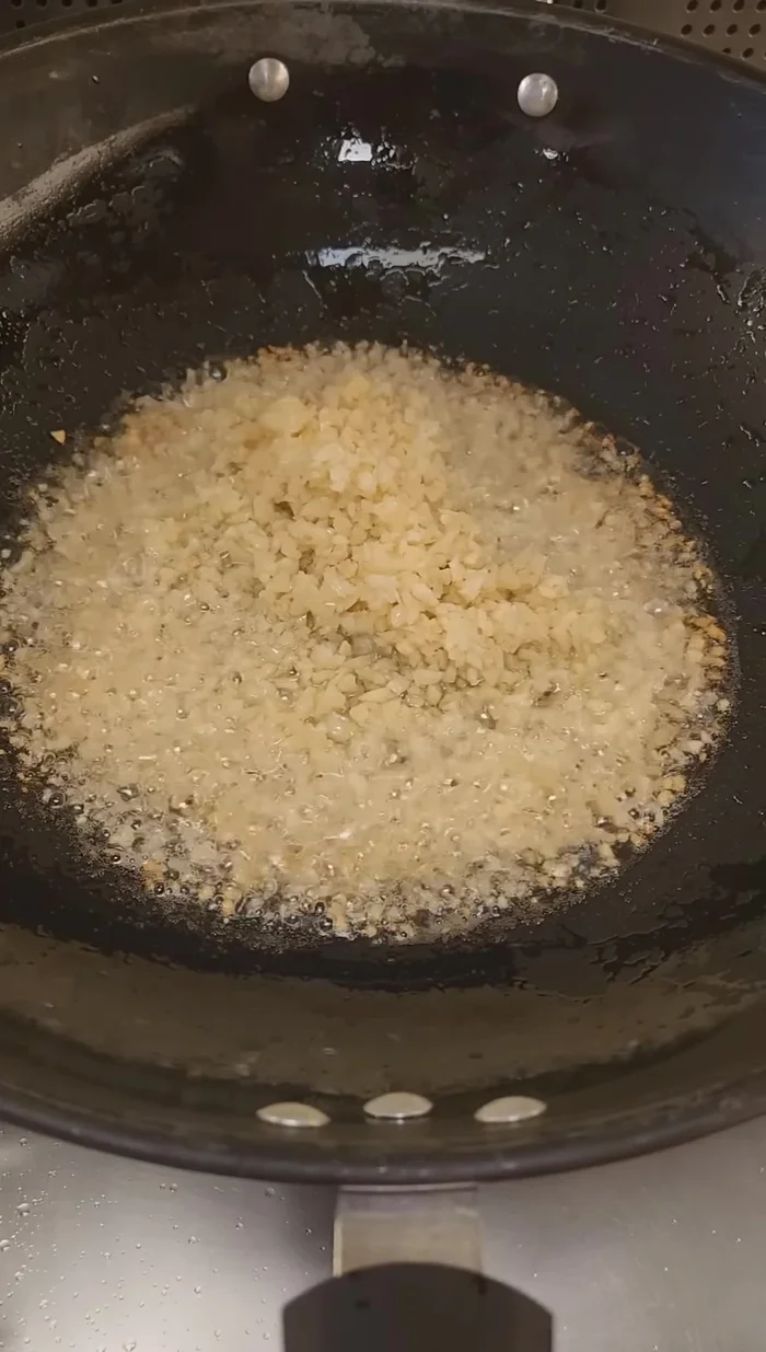 Heat wok, add oil, and add chopped garlic. Fry until dark brown.