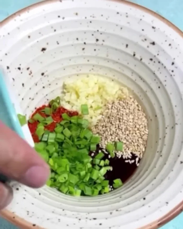 Prepare the sauce: Mix chopped garlic, chili powder, sugar, pesto sauce, sesame oil, white sesame seeds, spring onion, and light soy sauce.