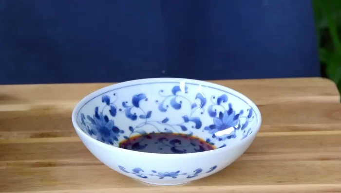 Nestle noodles in a bowl with seasoning sauce. Sprinkle with chili powder mixture and scallions, and top with crispy pork.