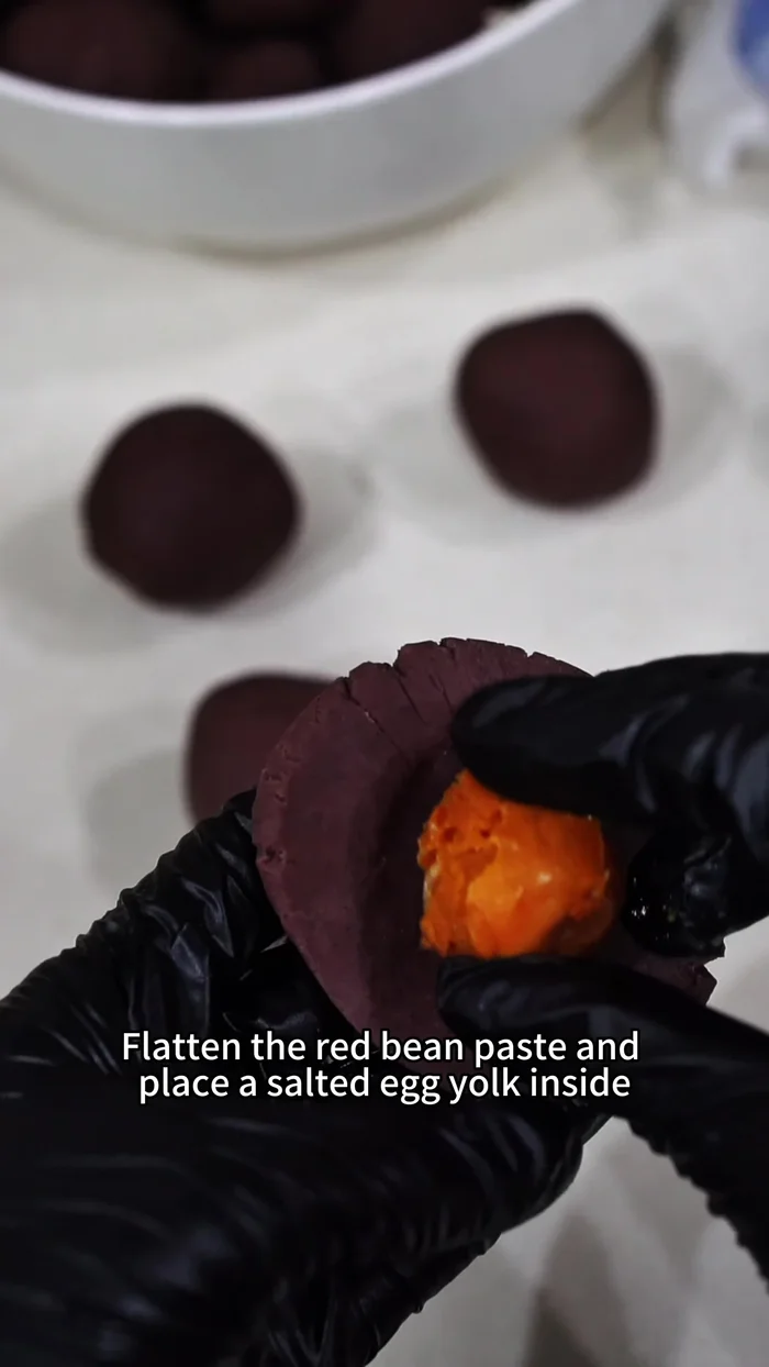 Make the filling: Flatten red bean paste and place a salted egg yolk (cooked or baked with scala liquor at 180°C for 5 minutes if raw) inside.