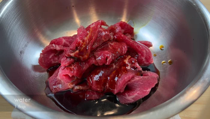 Marinate the beef with soy sauce, dark soy sauce, water, sugar, baking soda, and cornstarch. Mix well and add a touch of sesame oil.