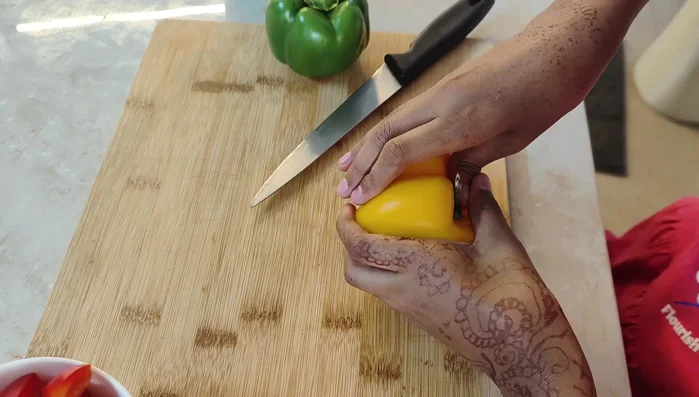 Cut red, yellow, and green capsicums into small squares.