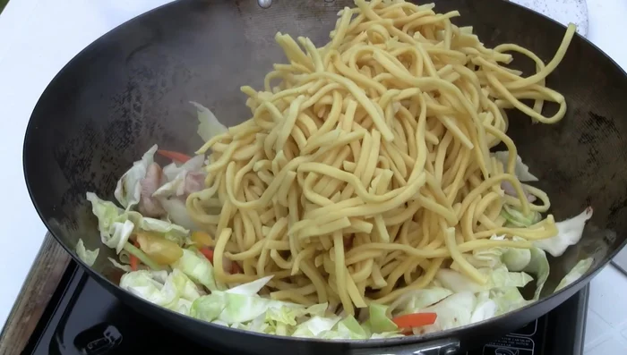 Add the noodles to the wok and toss to combine everything.