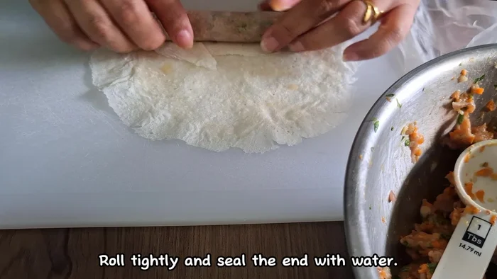 Scoop the mixture onto lumpia wrappers, roll tightly, and seal with water.