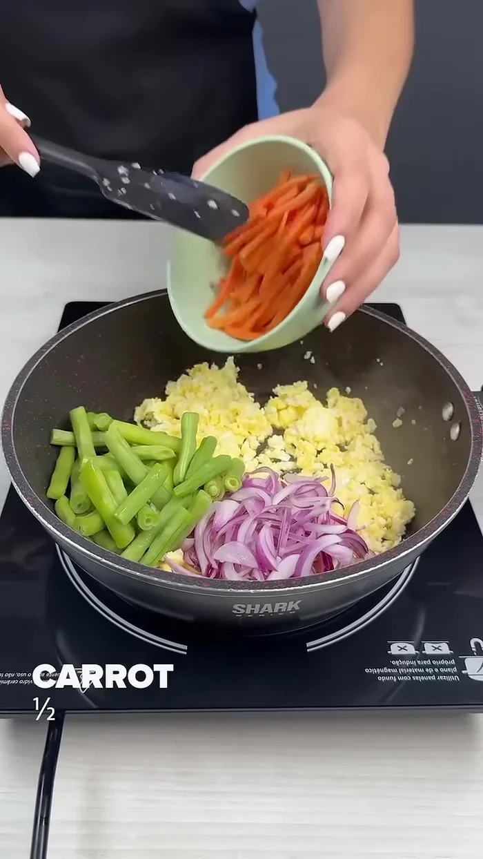 Add sliced onion, green beans, half a carrot, half a yellow bell pepper, half a green bell pepper, half a red bell pepper, and half a cabbage. Mix and fry for 5 minutes.