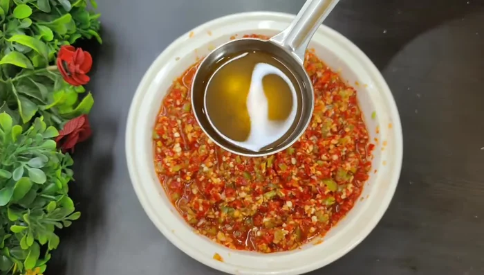 Remove the spices from the oil and pour the hot oil over the chili mixture.